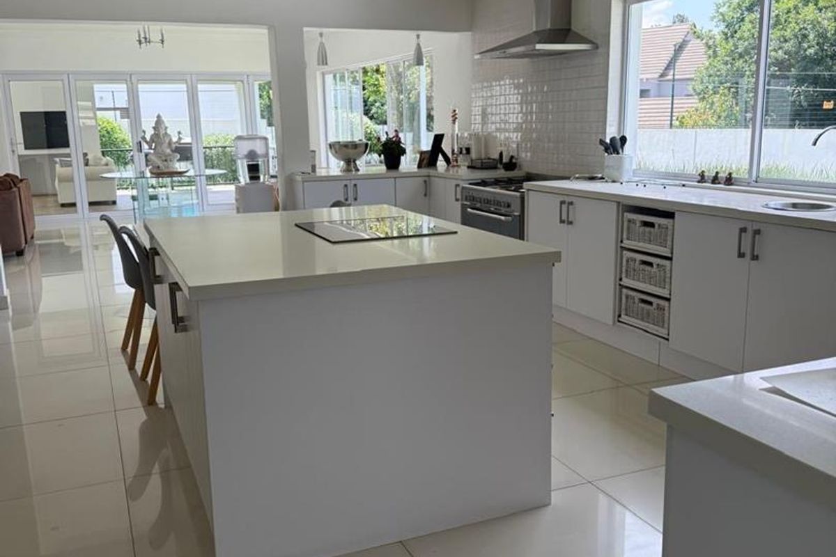 Modern, bright kitchen featuring a central island, quartz countertops, subway tile backsplash, and high-quality stainless steel appliances, flowing into an open-plan living area.