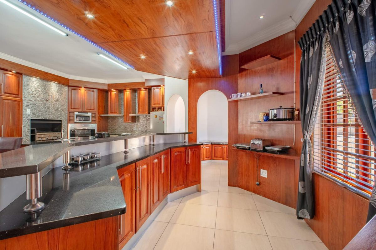 Spacious kitchen featuring dark wood cabinetry, granite countertops, built-in oven, and integrated lighting, offering a functional layout with ample storage and workspace.