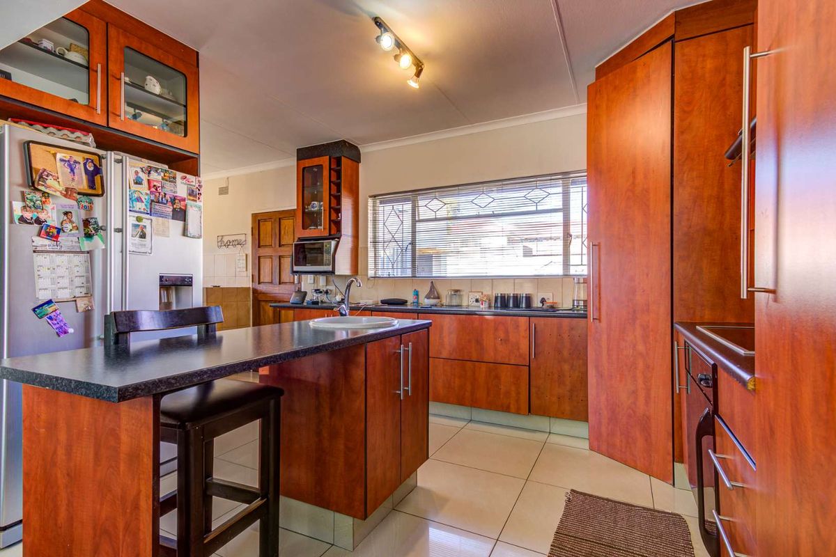 A functional kitchen featuring wood-veneer cabinetry, a central island with a breakfast bar, tiled flooring, and a built-in oven.