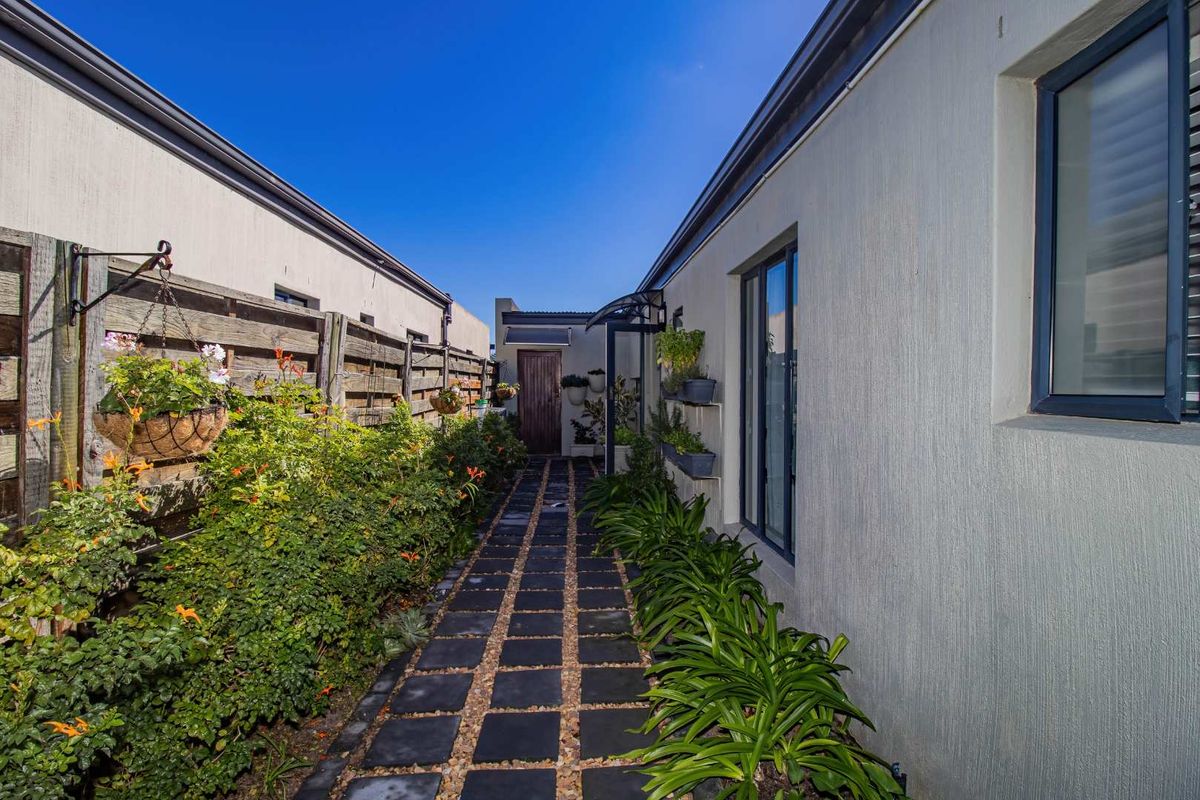 A well-maintained side walkway featuring paved stepping stones, landscaped garden beds, and a timber boundary fence.