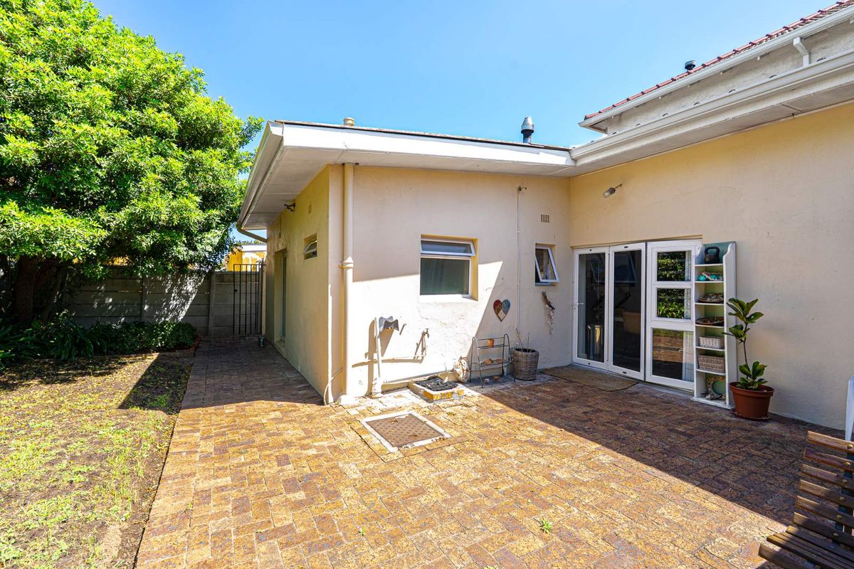 A private rear courtyard featuring paved flooring, direct access to the interior via glass doors, and a small garden area.