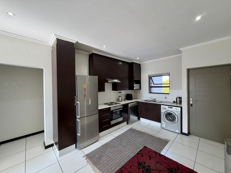 Modern kitchen featuring dark wood cabinetry, stainless steel appliances, tiled flooring, and recessed lighting, offering a clean and functional workspace.