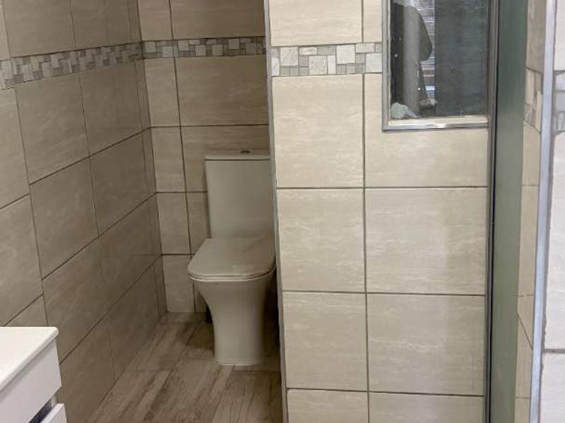 A clean, modern bathroom featuring neutral-toned wall and floor tiles, a built-in vanity, and a separate shower enclosure.