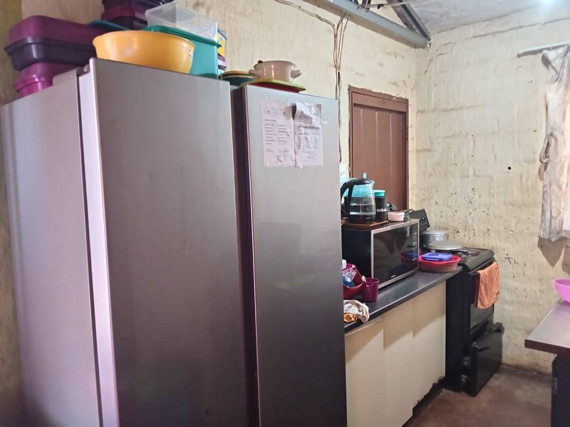 A functional kitchen area featuring a built-in stove and base cabinetry, currently showing significant wear on the wall surfaces and exposed electrical wiring.