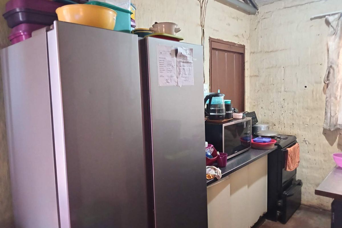 A functional kitchen area featuring a built-in stove and base cabinetry, currently showing significant wear on the wall surfaces and exposed electrical wiring.