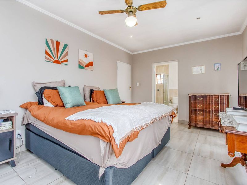 Spacious bedroom featuring tiled flooring, a ceiling fan, and direct access to an en-suite bathroom.