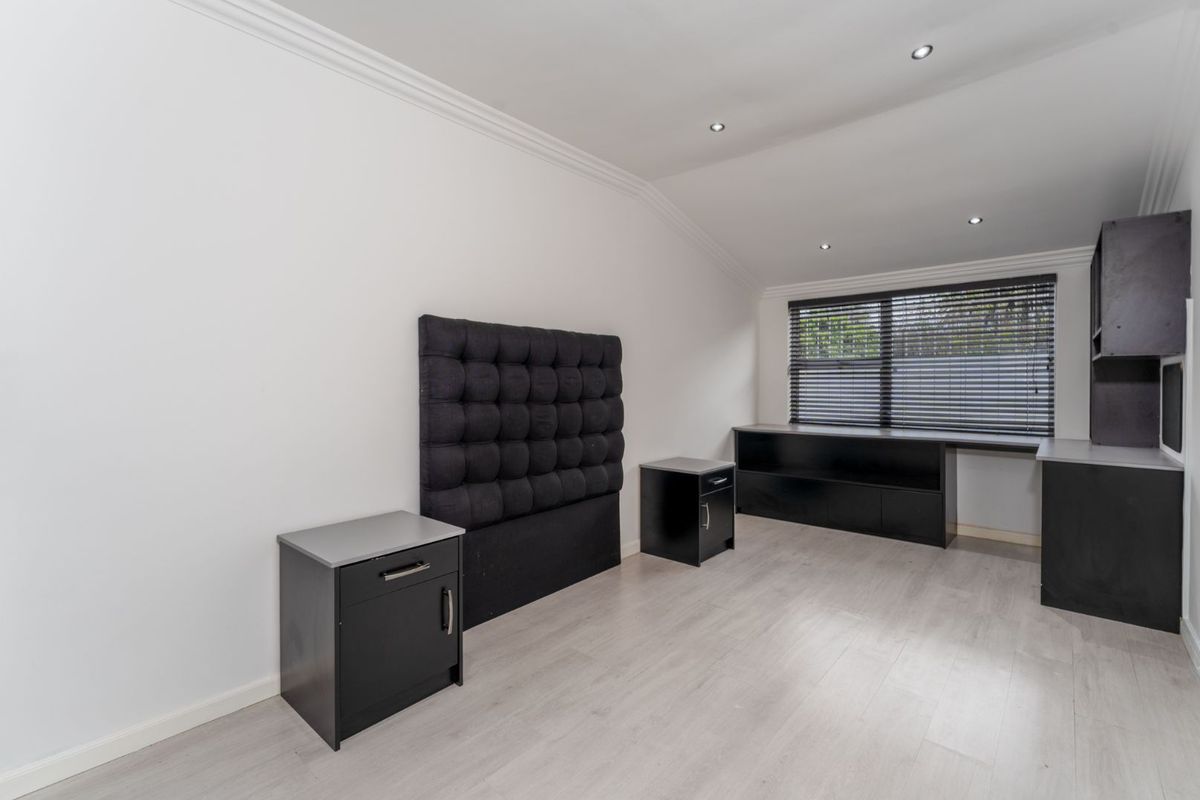 A bedroom featuring light wood-look flooring, recessed ceiling lighting, and built-in black cabinetry with a matching headboard panel.