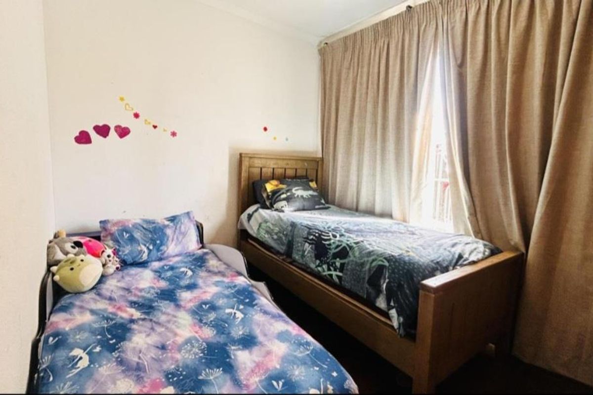 A functional bedroom featuring a window with full-length curtains and neutral wall finishes.