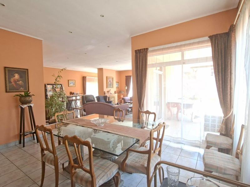 Spacious open-plan living and dining area featuring tiled flooring, recessed lighting, and large sliding glass doors providing access to the patio.