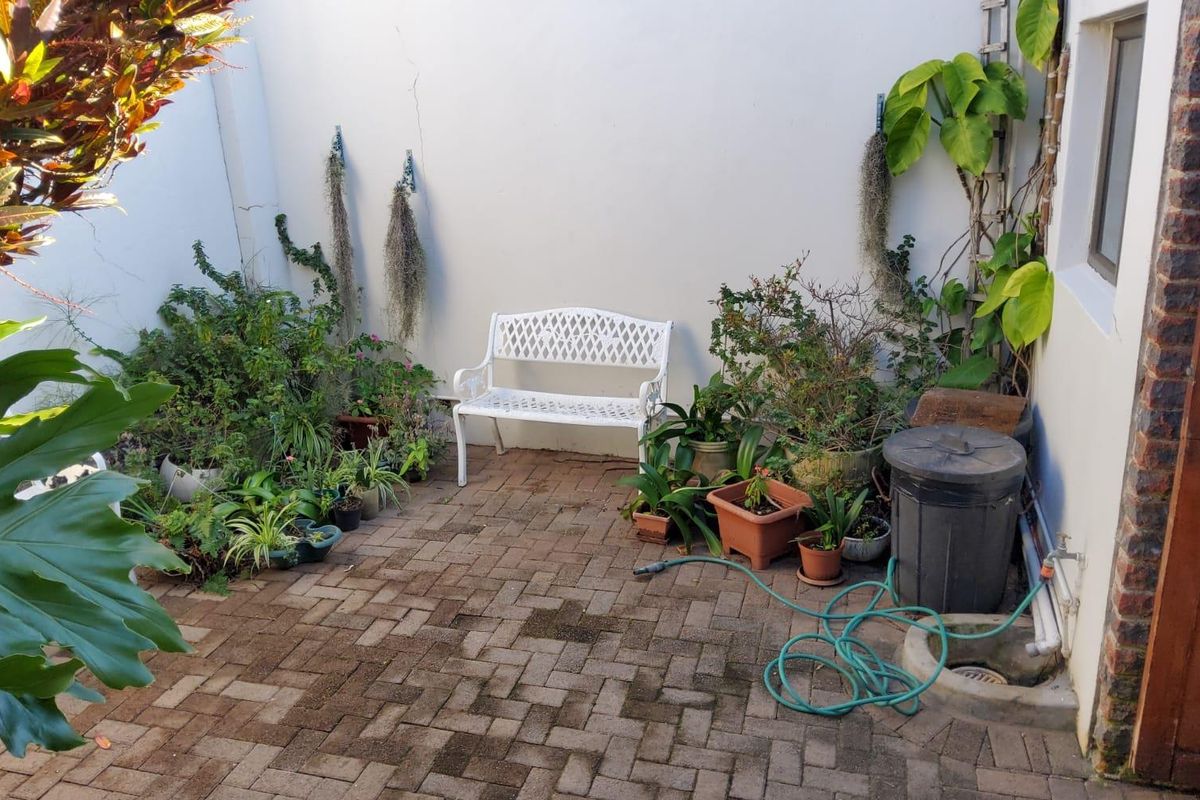 A small paved rear courtyard area featuring a brick-paved surface, external water tap, and a boundary wall with visible surface cracking.