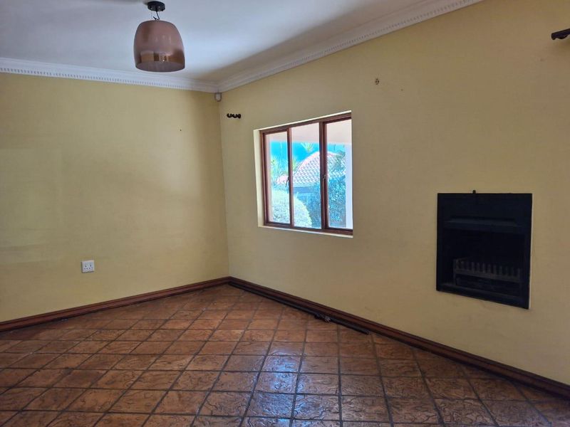 An empty living room featuring tiled flooring, crown molding, and a built-in fireplace, offering a blank canvas for interior design.