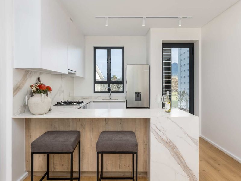 Modern kitchen featuring marble-look stone countertops, built-in cabinetry, gas hob, and integrated appliances, finished with high-quality materials and contemporary track lighting.