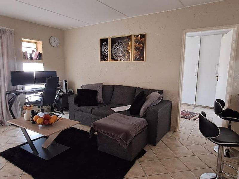Open plan living area featuring tiled flooring and a sliding glass door leading to the exterior, with an adjacent view into a bedroom.