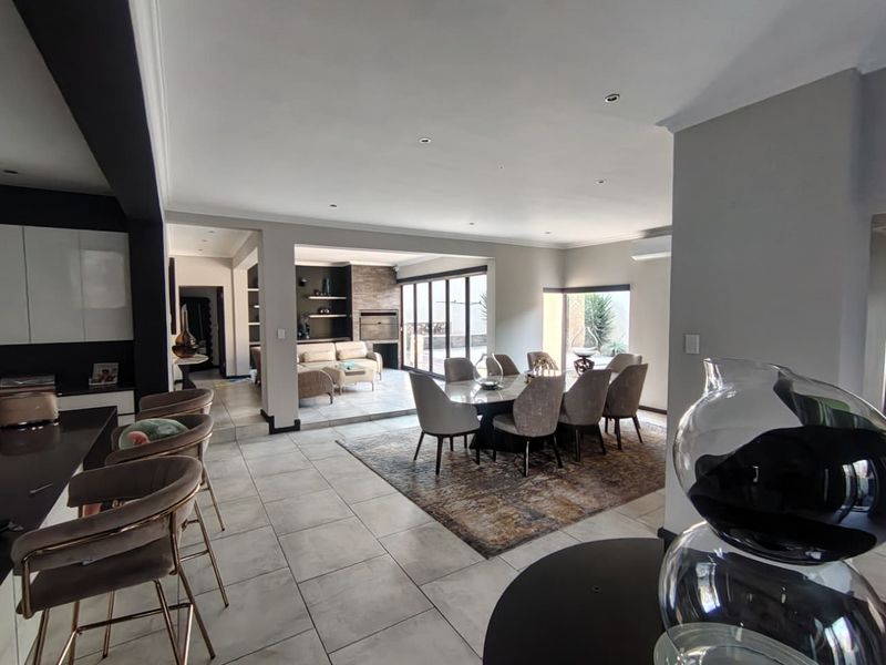 Spacious open-plan living and dining area featuring tiled floors, recessed lighting, a built-in fireplace, and large sliding doors leading to the outdoor space.