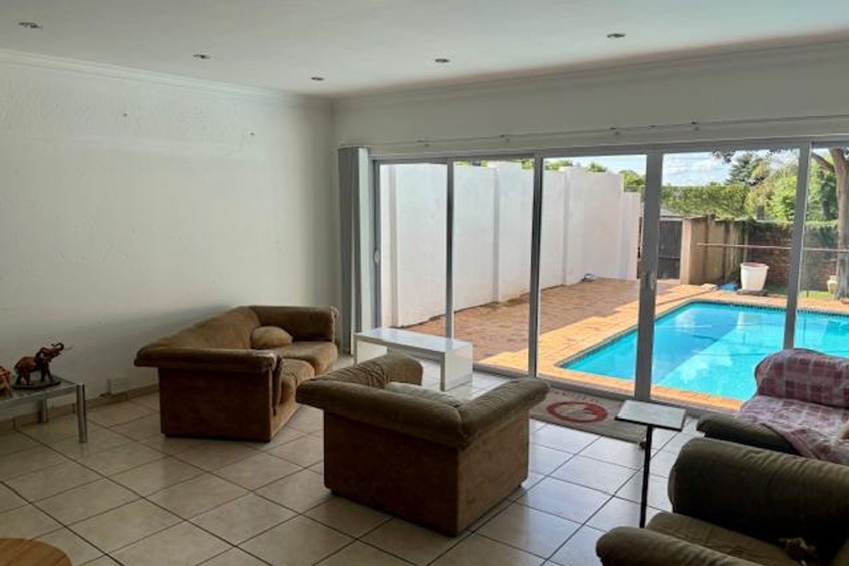 Spacious living area featuring large sliding glass doors that open directly onto a private swimming pool and patio area.