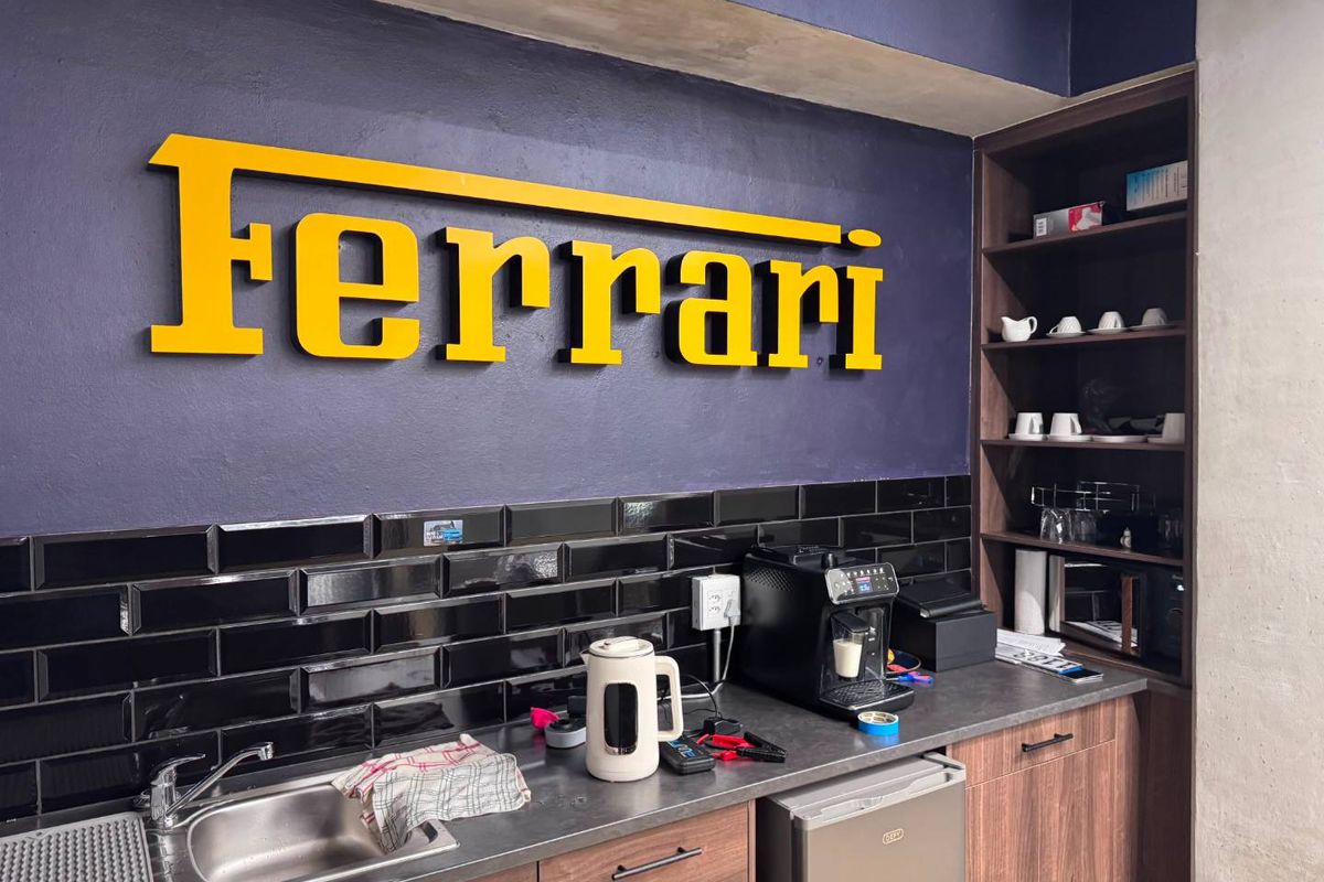 A compact kitchenette area featuring dark cabinetry, a subway tile backsplash, and a stainless steel sink, suitable for office or retail staff use.