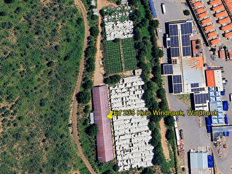Aerial view of a mixed-use property featuring industrial buildings with solar panel installations, paved access areas, and adjacent railway infrastructure.
