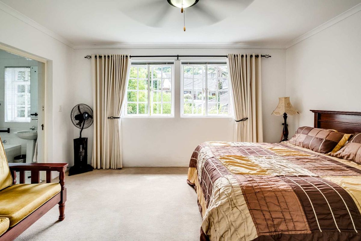 Spacious bedroom featuring neutral carpeting, a ceiling fan, and an adjoining en-suite bathroom with a pedestal sink.