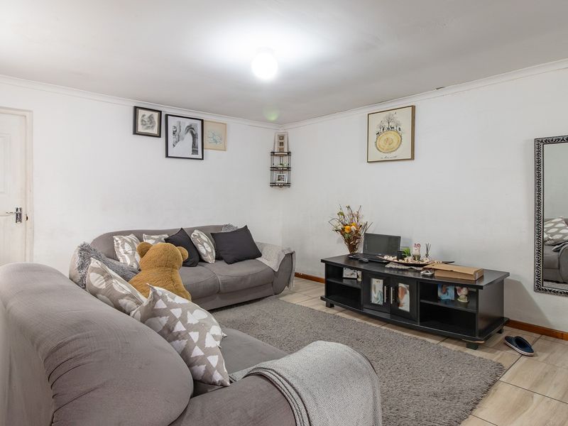 A living room featuring tiled flooring and coved ceilings, providing a functional space with potential for cosmetic updates to enhance the interior finish.
