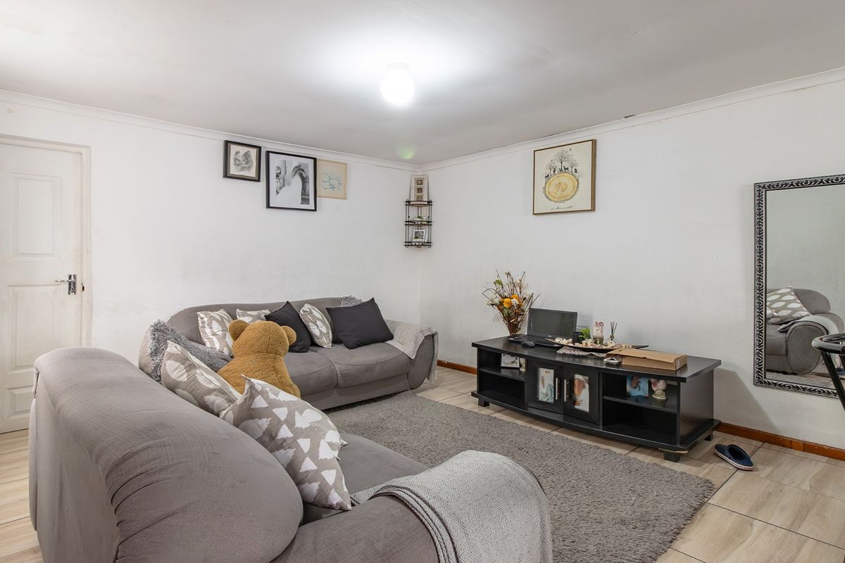 A living room featuring tiled flooring and coved ceilings, providing a functional space with potential for cosmetic updates to enhance the interior finish.