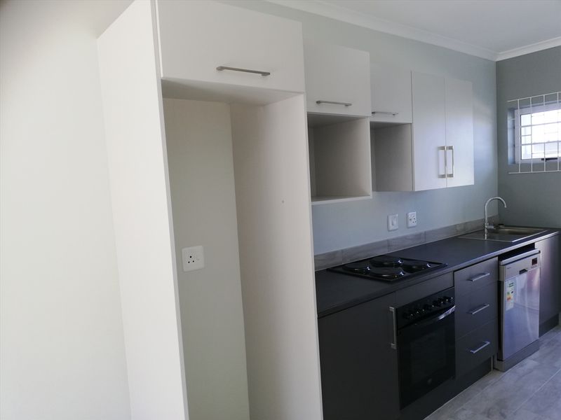 Modern kitchen featuring dark base cabinetry, white overhead storage, integrated dishwasher, built-in oven, and electric hob with a tiled backsplash.