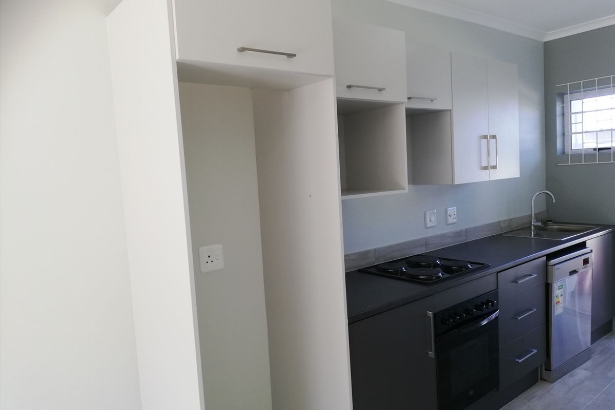 Modern kitchen featuring dark base cabinetry, white overhead storage, integrated dishwasher, built-in oven, and electric hob with a tiled backsplash.