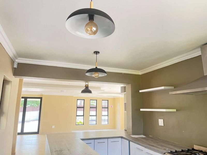 Spacious open-plan kitchen and living area featuring modern cabinetry, laminate countertops, built-in hob, extractor fan, and neutral finishes throughout.