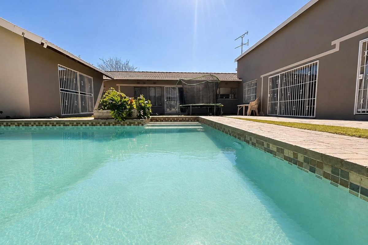 A well-maintained swimming pool area featuring paved surrounds and secure access to the main house structure.