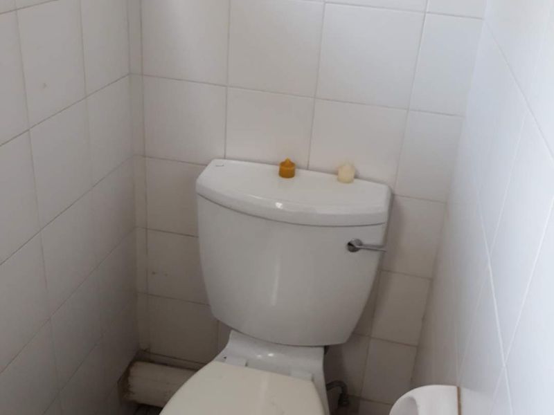 A compact, tiled bathroom featuring a standard toilet and basic fixtures, requiring some cosmetic updates to improve its overall appearance.