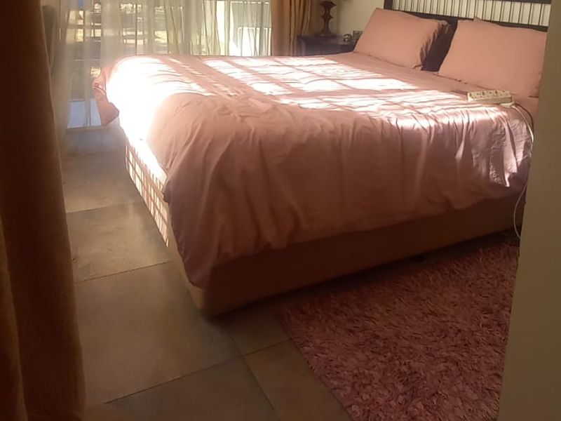 A bedroom featuring large format floor tiles and a sliding glass door providing natural light and access to the exterior.
