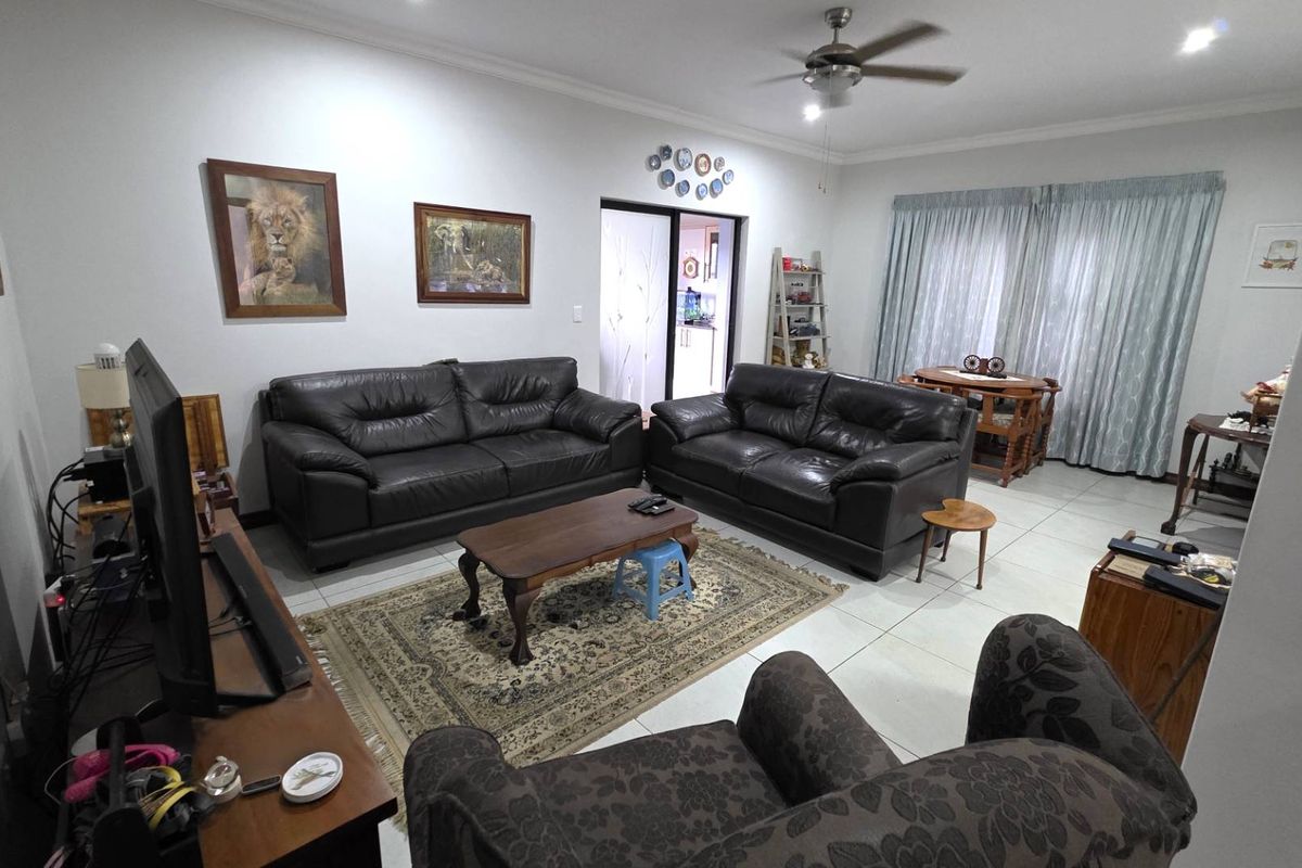 Spacious living room featuring tiled flooring, a ceiling fan, and recessed lighting, with direct access to an adjoining area through a sliding glass door.