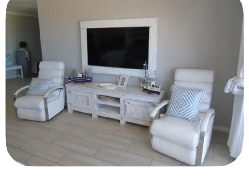 A bright living room featuring neutral tiled flooring and decorative coving, providing a clean and comfortable space for relaxation.