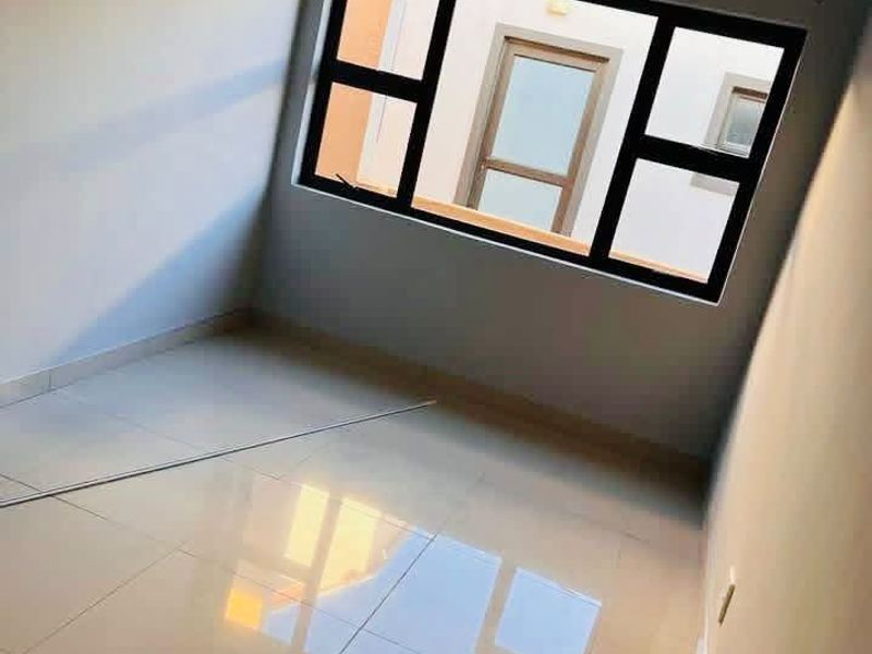A bright, empty bedroom featuring modern tiled flooring and large aluminium-framed windows, offering a clean and neutral space ready for personalization.