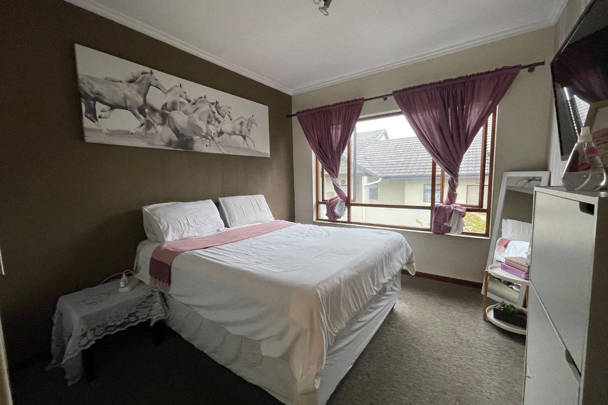 A bedroom featuring carpeted flooring, a large window with natural light, and neutral wall finishes.