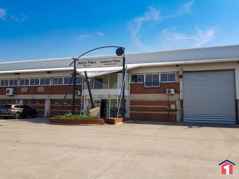 Front elevation of an industrial property featuring a large roller shutter door, brick facade, and a prominent glass entrance canopy.