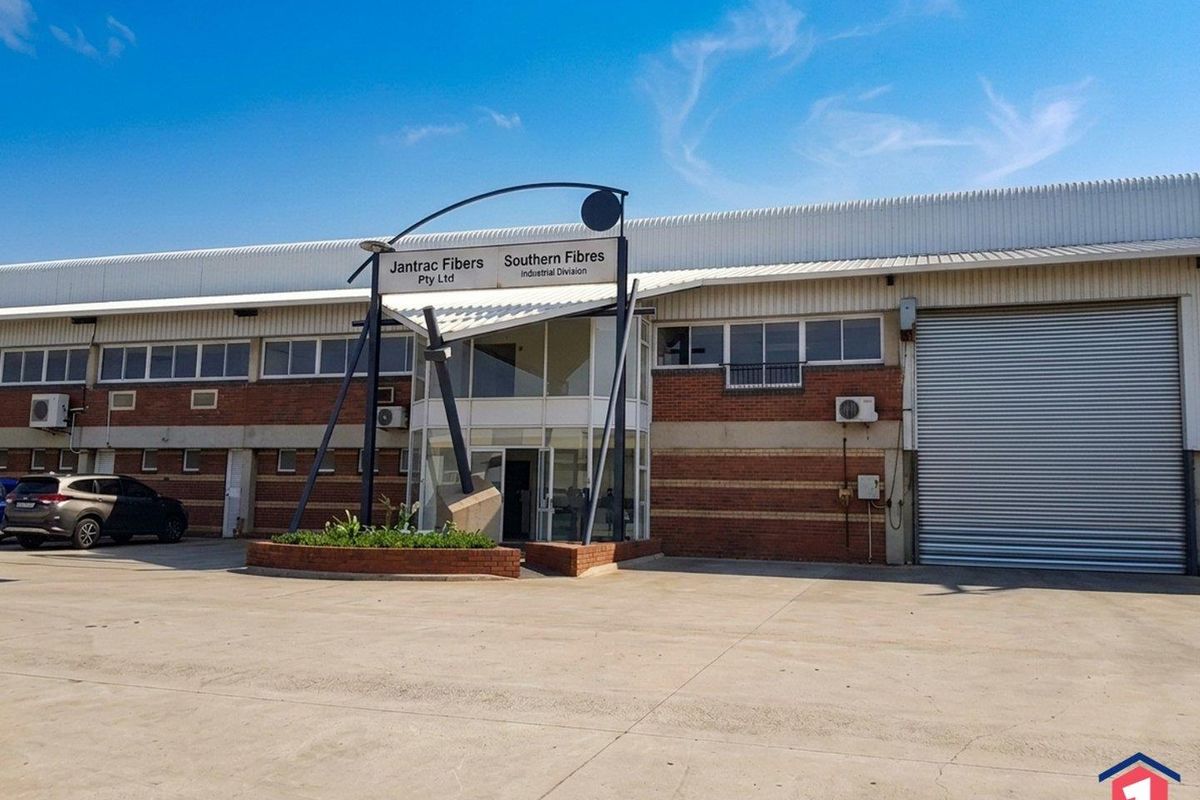 Front elevation of an industrial property featuring a large roller shutter door, brick facade, and a prominent glass entrance canopy.