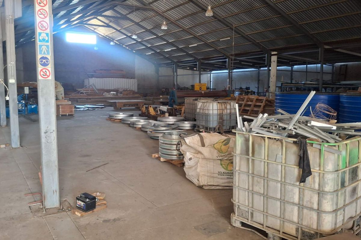 Spacious industrial warehouse featuring a steel portal frame structure, corrugated metal roofing, and durable concrete flooring, suitable for storage or manufacturing operations.