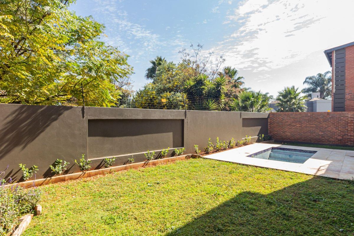 A private rear garden featuring a small swimming pool, paved surround, and a high perimeter boundary wall with security fencing.