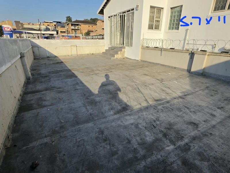 An expansive, open-air concrete balcony or terrace area featuring security fencing and direct access to the building exterior.