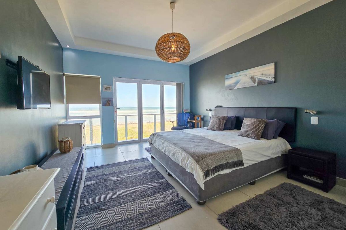 Spacious bedroom featuring tiled flooring, recessed ceiling lighting, and large glass sliding doors opening to a balcony with ocean views.