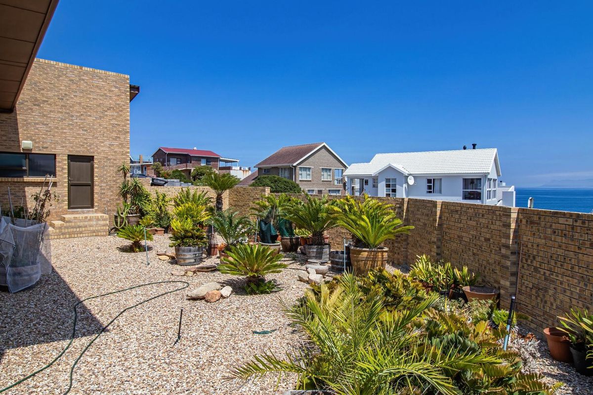 A low-maintenance rear garden area featuring gravel landscaping, brick boundary walls, and ocean views, providing a private outdoor space.