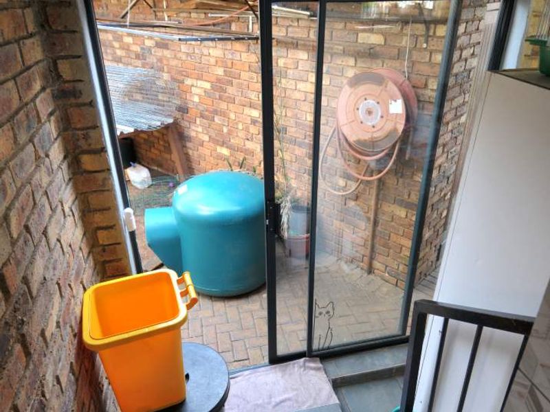 A small, enclosed patio area featuring brick walls, tiled flooring, and a sliding glass door leading to an outdoor space.