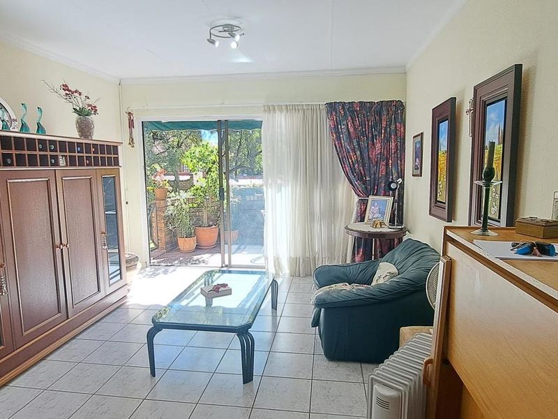 A living room featuring tiled flooring and a sliding glass door providing access to an outdoor patio area.