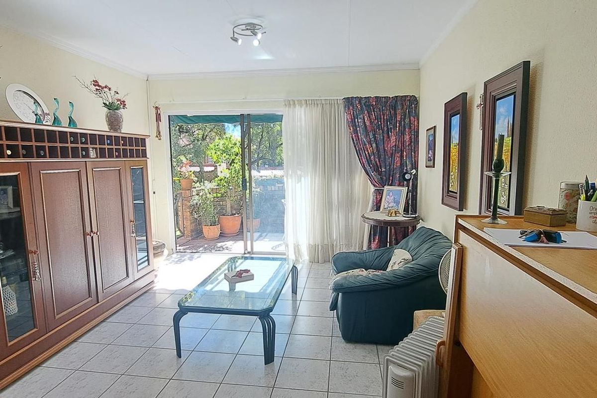 A living room featuring tiled flooring and a sliding glass door providing access to an outdoor patio area.
