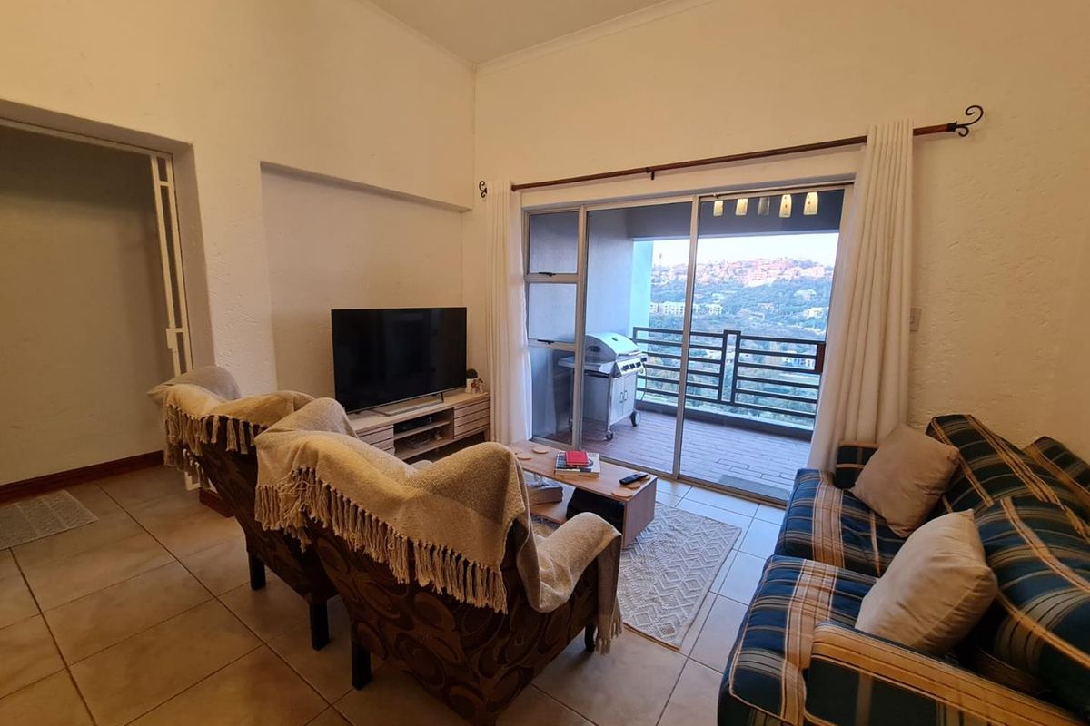 A comfortable living room featuring tiled flooring and large sliding glass doors that open onto a private balcony with scenic views.