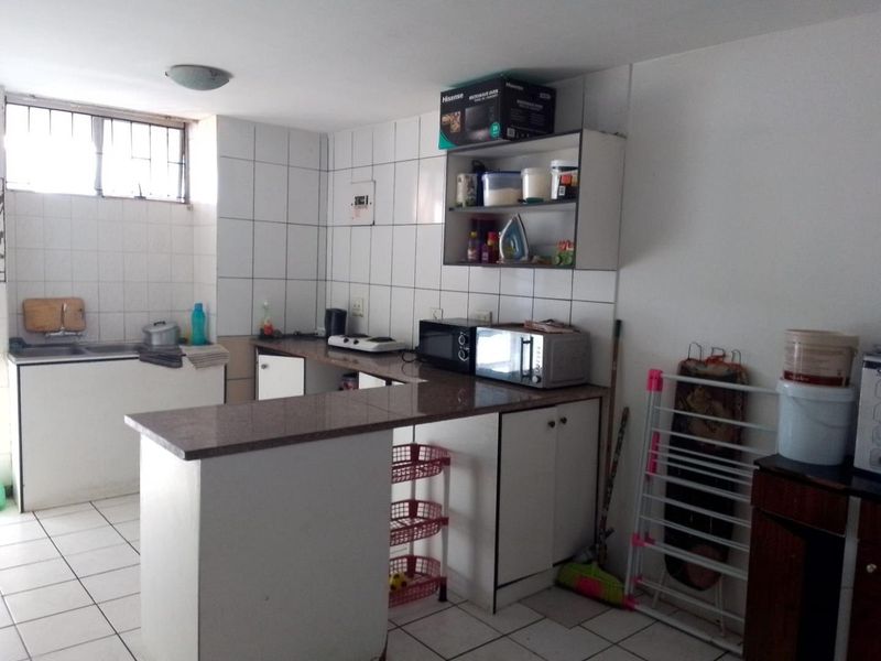 A functional kitchen featuring built-in cabinetry, granite countertops, a double sink, and tiled finishes throughout, offering a practical layout for daily use.