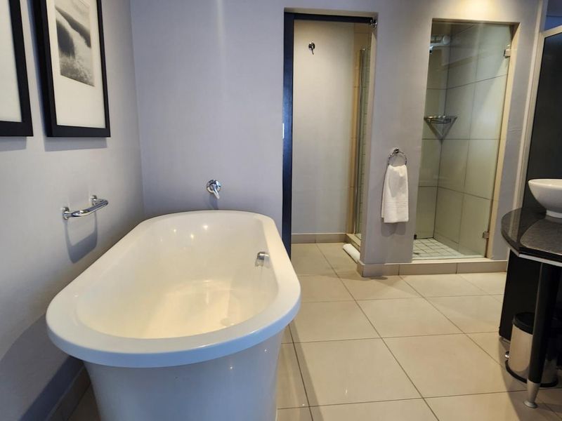 Modern bathroom featuring a sleek freestanding bathtub, a separate walk-in shower with glass enclosure, and a contemporary vessel sink vanity.