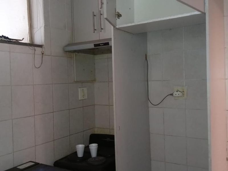 A compact kitchen area featuring tiled walls, built-in cabinetry, and a built-in stove with an extractor fan.