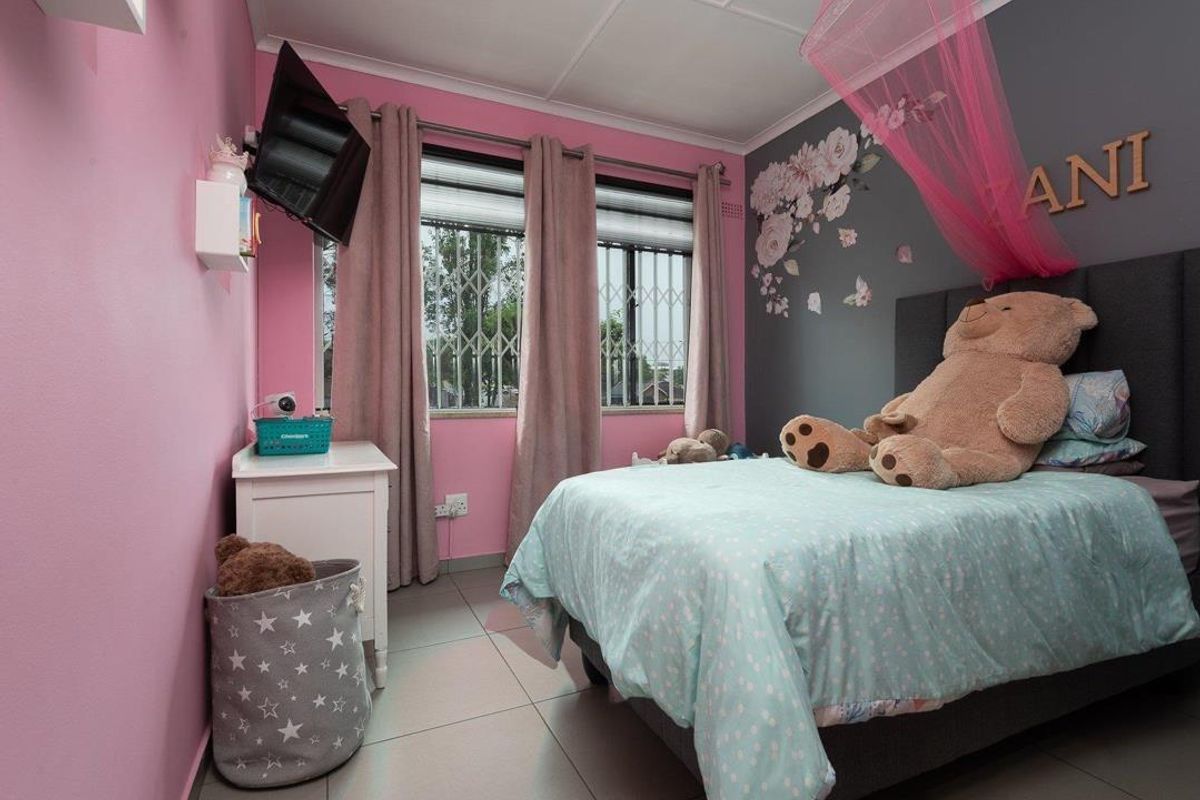 A bedroom featuring tiled flooring, security bars on the windows, and a feature wall.