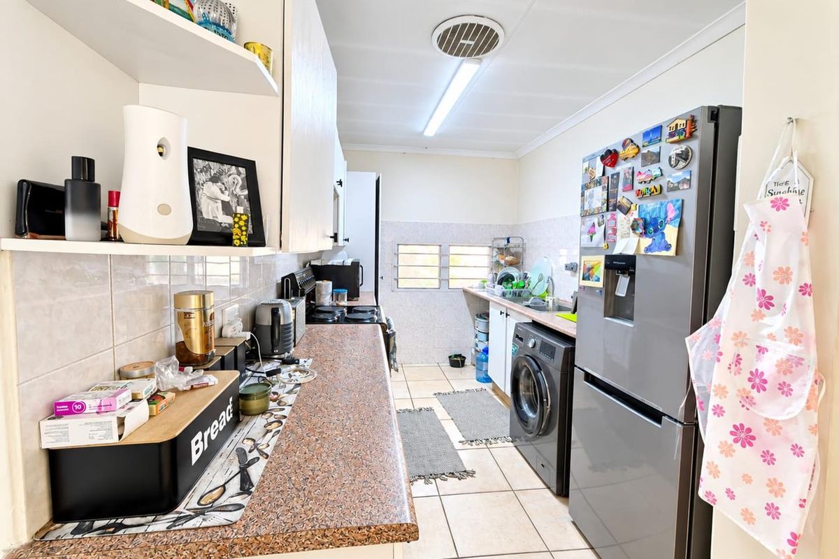 A functional kitchen featuring laminate countertops, tiled backsplash, ceramic flooring, and built-in cabinetry with integrated sink and appliance space.